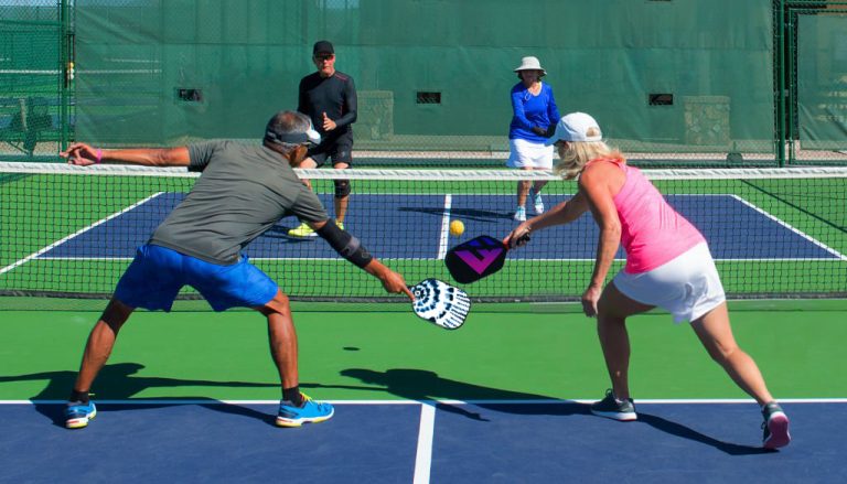 colorful action image of two couples playing pickleball in a mixed doubles match