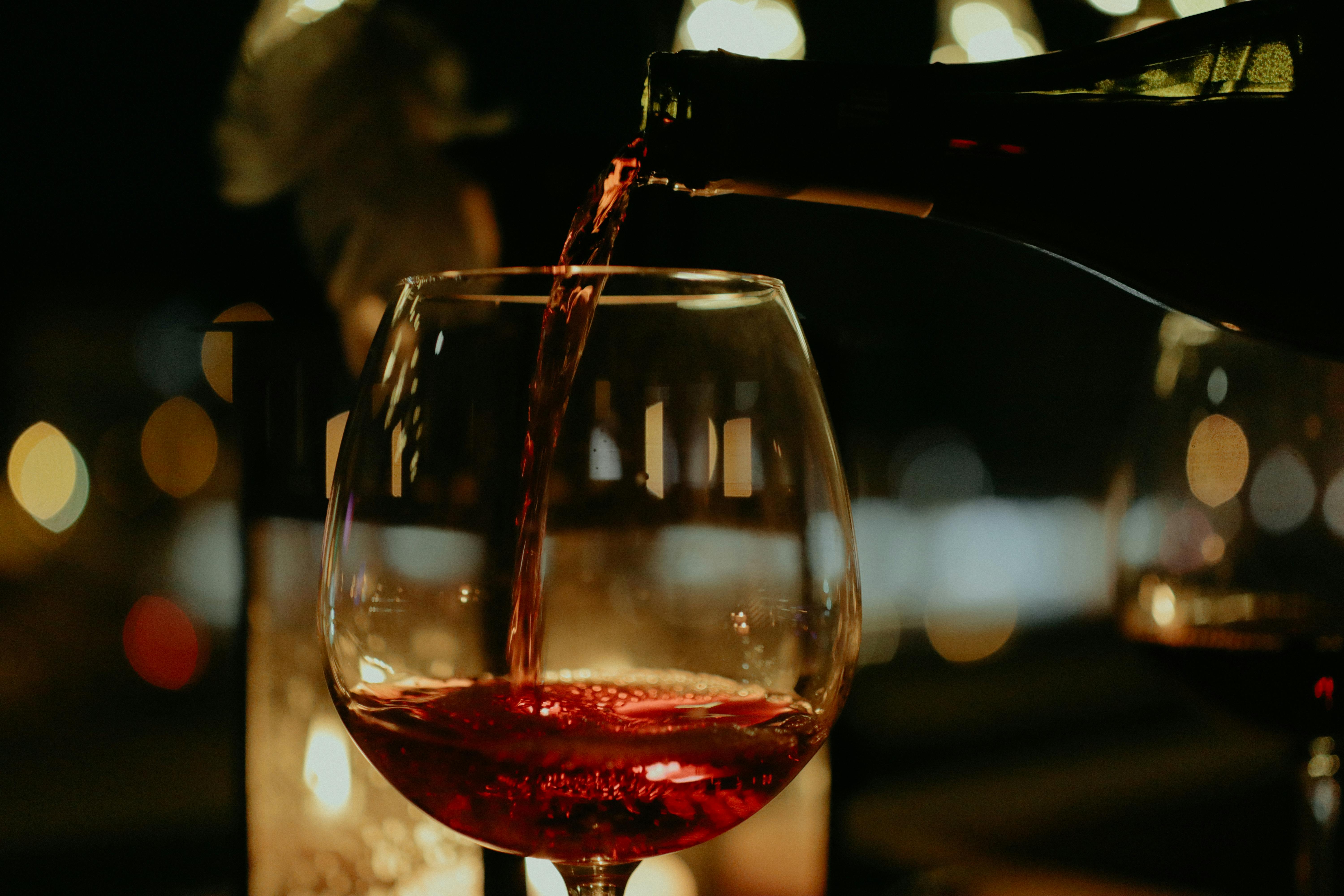 Pouring a glass of red wine in a dark bar
